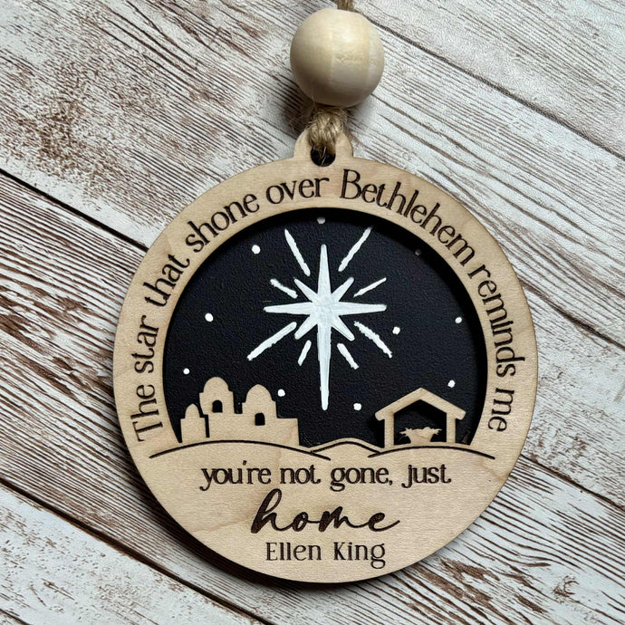 Decorative wooden ornament with star and nativity scene design on a wooden surface personalized memorial ornament